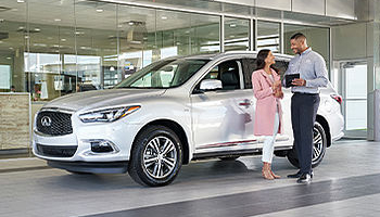 Woman talking to INFINITI dealer in front of White INFINITI
